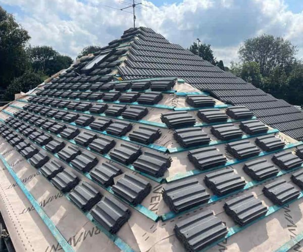 This is a photo of a new hip roof being installed. New felt, battens, and grey tiles have been installed, also a new velux window. Works carried out by LPO Roofing Kempston